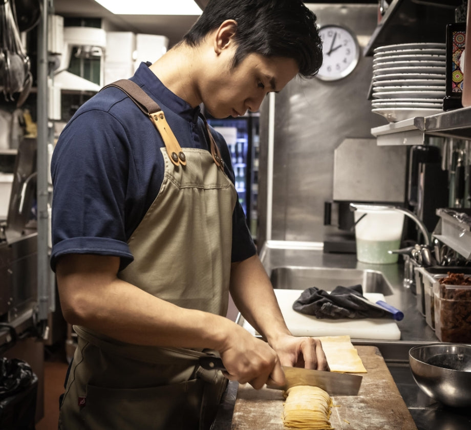 Man chopping in kitchen wearing an apron